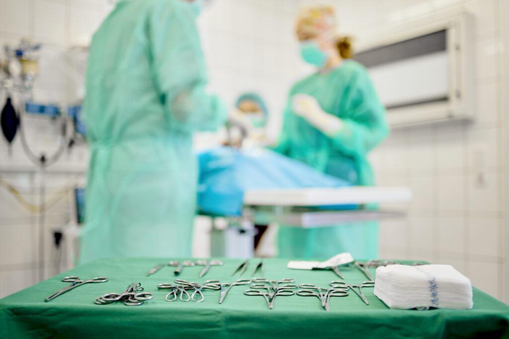 40-Chirurgie-OP-Besteck-Kleintierpraxis-am-Hirschgraben OP Besteck im Vordergrund. Im Hintergrund Tierärzte in OP-Kitteln am operieren.